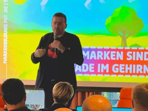 Christian Dietz mit Mikrofon bei DENIC vor der Folie Marken sind Trampelpfade im Gehirn