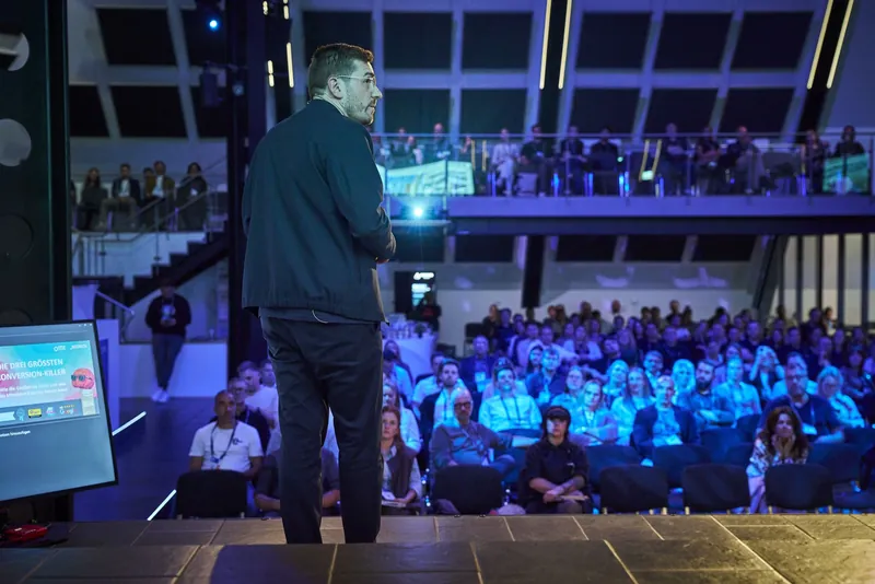 Blick von der Bühne beim OMT 2026: Christian Dietz vor einem vollen Saal mit besetzter Empore